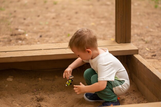 Schattige kleine blanke jongen die in de zomer in de speeltuin speelt