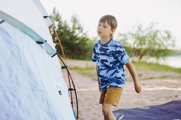 Schattige kleine blanke jongen helpt een tent op te zetten Familie camping concept