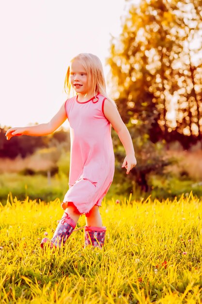 Schattige kleine blonde ggirl in een weide in zonnige zomerdag