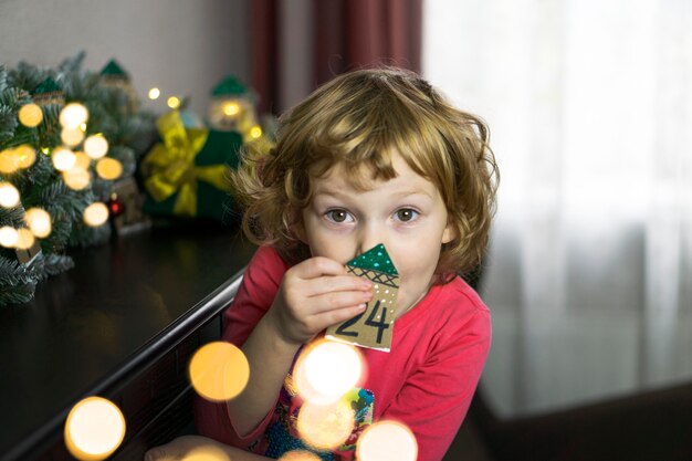 Foto schattige kleine blonde met de nummer 24 adventskalender. kersttradities op kerstavond.