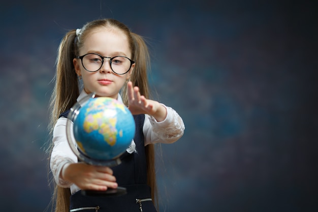 Schattige kleine blonde schoolmeisje houden wereldbol