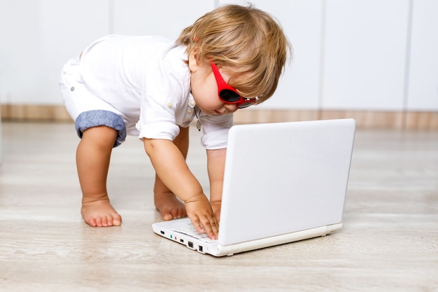 Schattige kleine Europese slimme jongen met blond haar die plezier heeft met een computer thuis