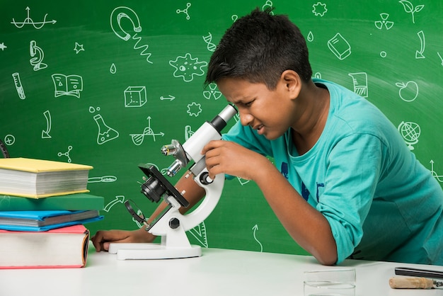 Schattige kleine Indiase Aziatische schooljongen student experimenteert of studeert wetenschap in laboratorium, over groene schoolbordachtergrond met educatieve doodles