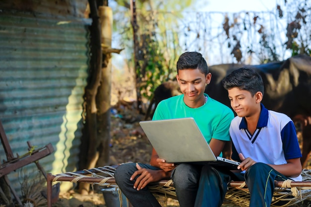 Schattige kleine Indische / Aziatische jongen die of spel met laptop computer bestudeert speelt