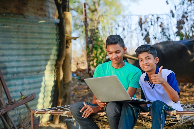 Schattige kleine Indische / Aziatische jongen die of spel met laptop computer bestudeert speelt