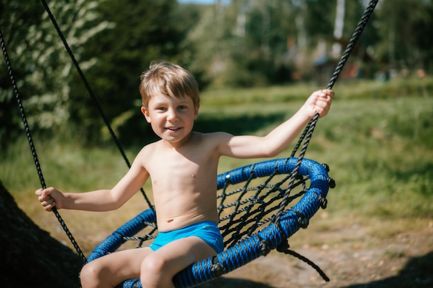 Schattige kleine jongen die plezier heeft op een schommel in de speeltuin