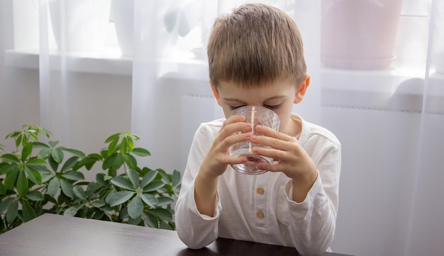 Schattige kleine jongen drinkt water uit een glas