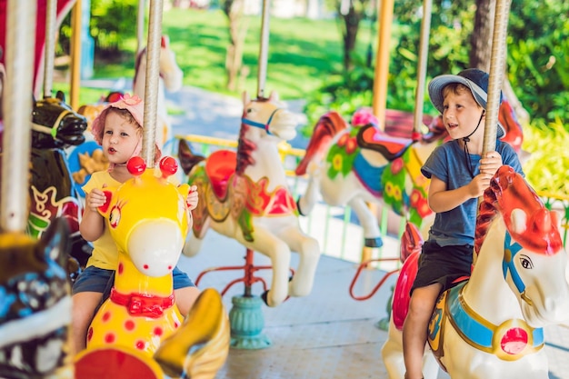 Schattige kleine jongen en meisje genieten op de kermis en rijden op een kleurrijk carrouselhuis