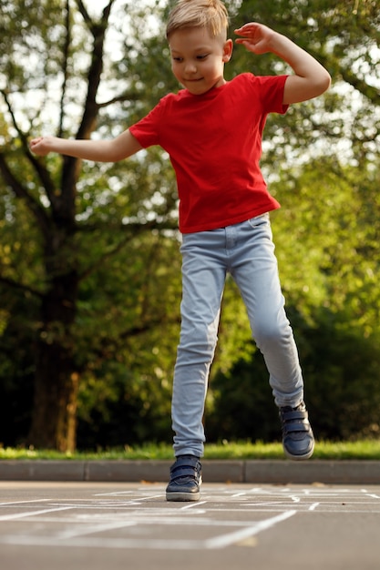 Schattige kleine jongen Hinkelspel buiten. Straat kinderspelen. Selectieve aandacht.