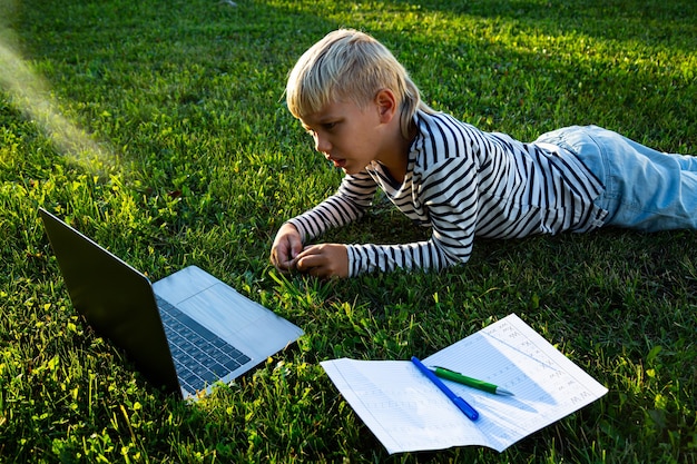 Schattige kleine jongen huiswerk in de natuur