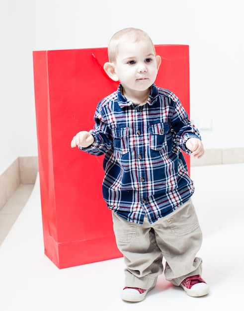 Schattige kleine jongen in een rood pakket. concept van eigen speelgoedhuis