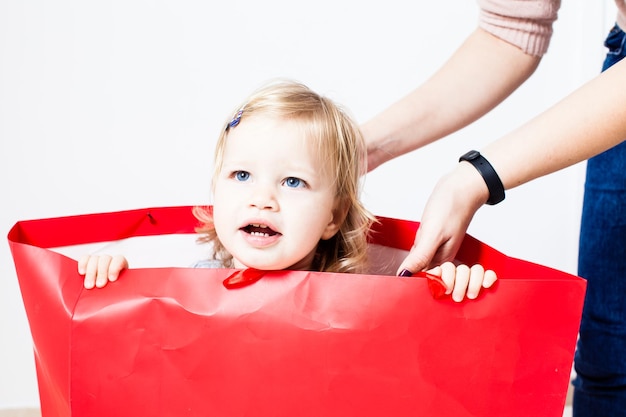 Schattige kleine jongen in een rood pakket. Concept van eigen speelgoedhuis