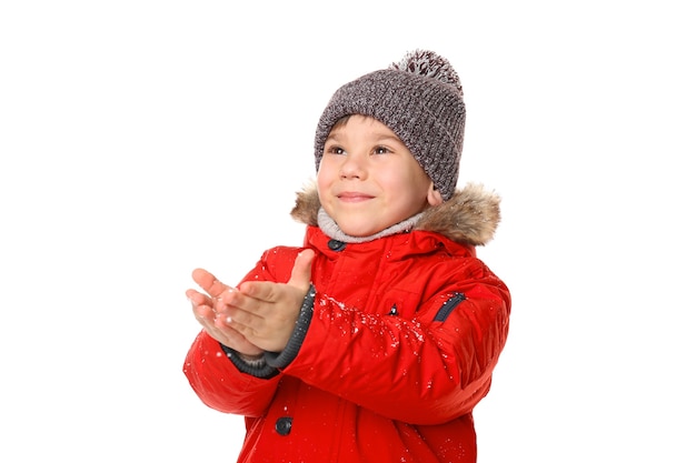 Schattige kleine jongen in warme kleren spelen met sneeuw