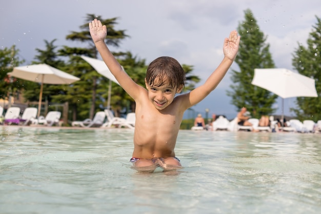 Schattige kleine jongen jongen kind spetteren in zwembad met leuke vrijetijdsbesteding