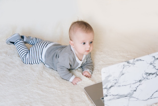 Schattige kleine jongen liegen en op zoek naar laptop