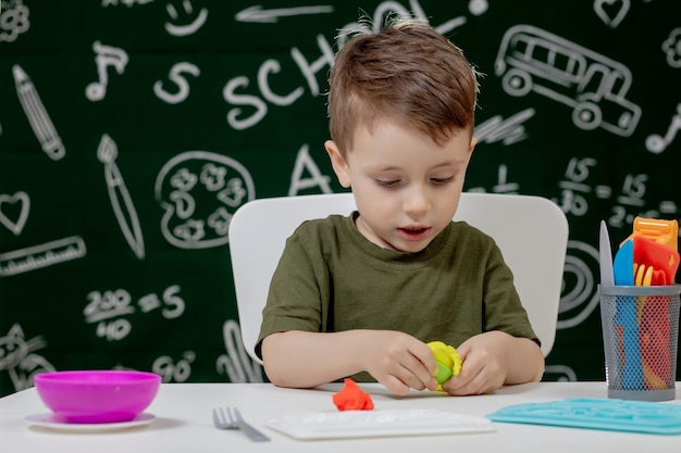 Schattige kleine jongen mallen van plasticine op tafel