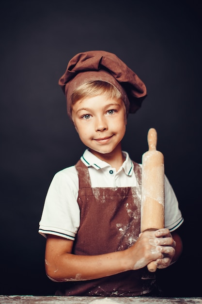 Schattige kleine jongen met chef-kok hoed koken