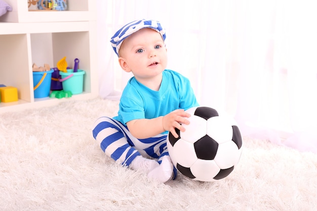 Schattige kleine jongen met voetbal in de kamer