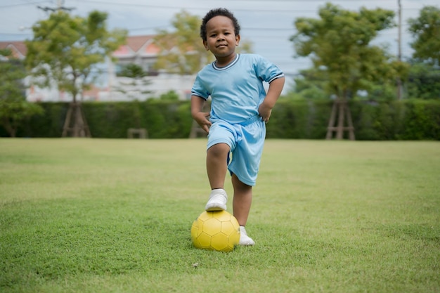 Schattige kleine jongen met voetbal in het park op een zonnige dag