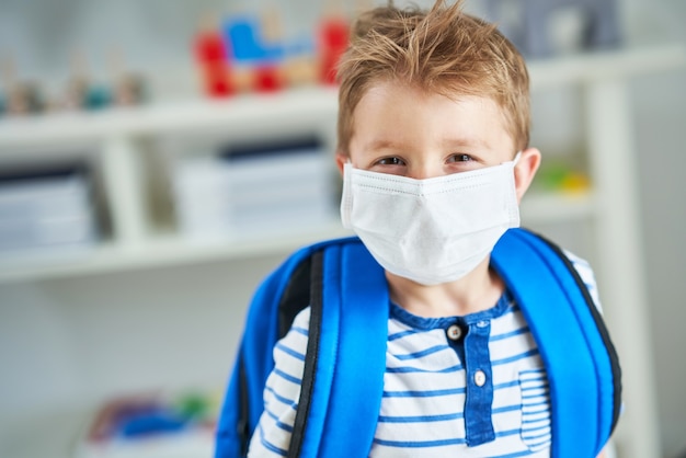 Schattige kleine jongen op de kleuterschool met masker op vanwege de pandemie van het coronavirus