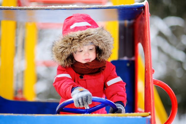 Schattige kleine jongen plezier op speelplaats. Winter buiten plezier voor peuter kinderen