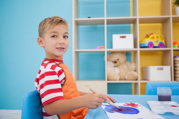 Schattige kleine jongen schilderij aan tafel in de klas