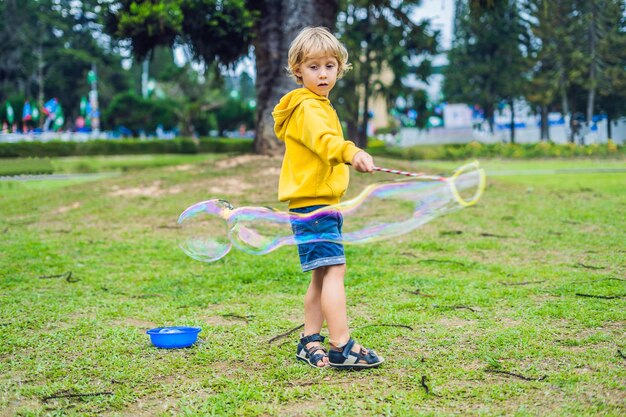 Schattige kleine jongen speelt buiten met grote bubbels