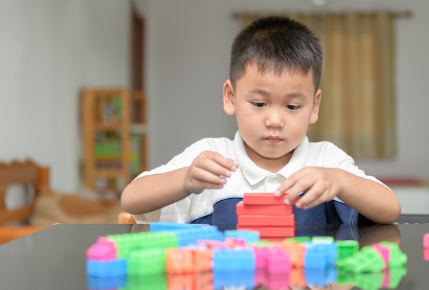 Schattige kleine jongen speelt hout baksteen