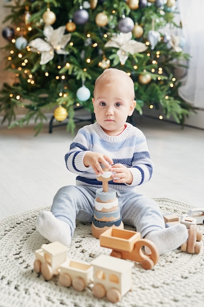 Schattige kleine jongen speelt met speelgoed houten trein, speelgoedauto, piramide en kubussen, leren ontwikkelingsconcept. Ontwikkeling van fijne motoriek van kinderen, verbeelding en logisch denken