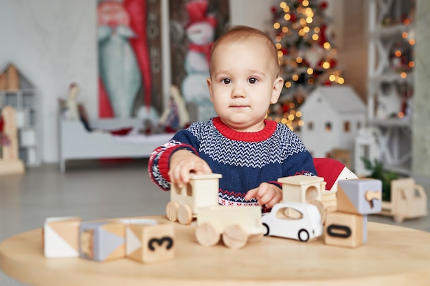 Schattige kleine jongen speelt met speelgoed houten trein, speelgoedauto, piramide en kubussen, leren ontwikkelingsconcept. Ontwikkeling van fijne motoriek van kinderen, verbeelding en logisch denken