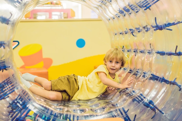 Schattige kleine jongen, spelend in Zorb een rollende plastic cilinderring met een gat in het midden, binnen.
