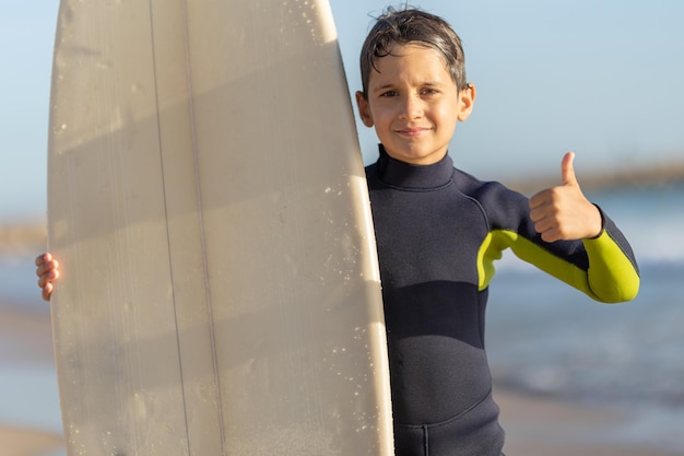 Schattige kleine jongen surfer met een duim omhoog