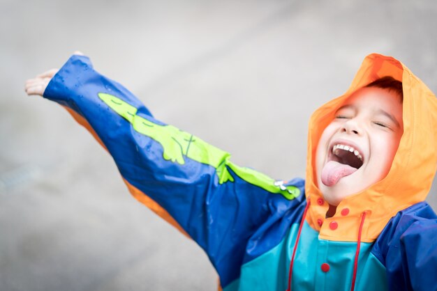 Schattige kleine jongen uit voor het proeven van regen