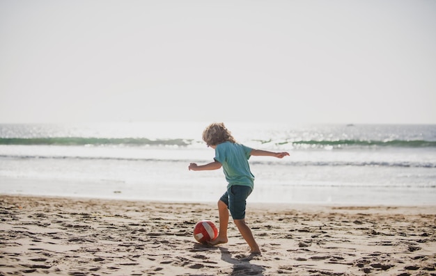 Schattige kleine jongen voetballen met voet bal op zandstrand zomer kid sport