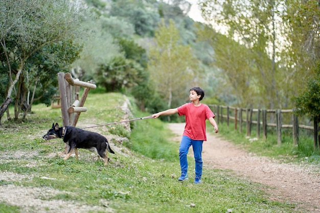 Schattige kleine jongen, wandelend met zijn kleine hondje in een landelijk koolzaadveld naast hem, jongen die op een klein pad loopt