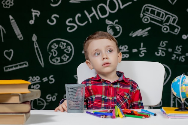 Schattige kleine jongen zit aan een bureau