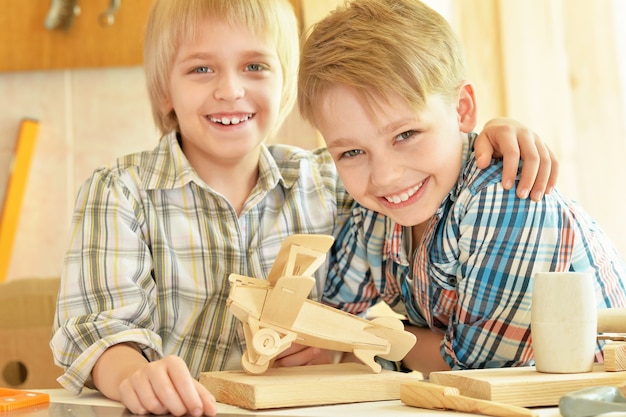 Schattige kleine jongens werken met hout in werkplaats