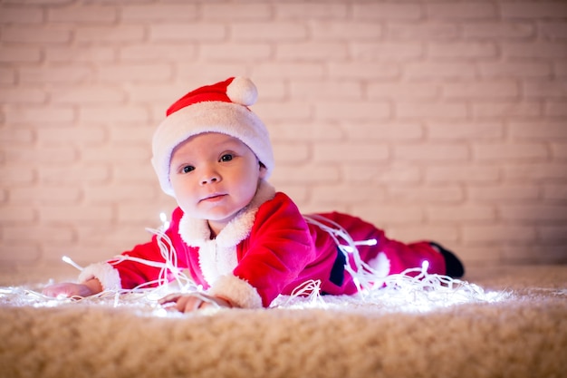 Schattige kleine kerstman baby spelen met kerstverlichting