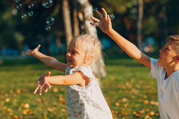 Schattige kleine kinderen jongen en meisje bellen blazen in herfst park op zonnige dag.