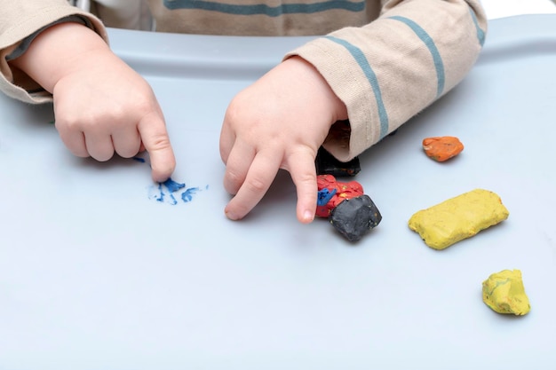 Schattige kleine kinderhanden die thuis spelen, vormen veelkleurige plasticine beeldhouwt met gekleurd kleistucwerk Playdough klei modellering kunst creativiteit ambacht op de kleuterschool