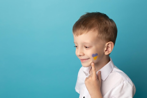 Schattige kleine lachende jongen met een vlag van Oekraïne op zijn wang