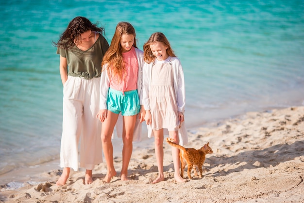 Schattige kleine meisjes en jonge moeder op tropisch wit strand