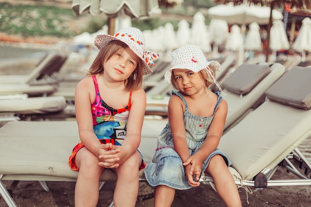 schattige kleine meisjes op het strand met chaise-longue