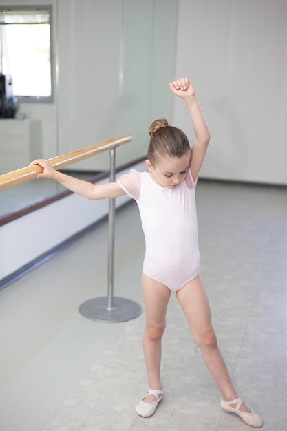 Schattige kleine meisjespeuterballerina in lichtroze tutu en balletschoenen die dansbewegingen beoefenen.