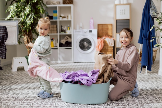 Schattige kleine schattige meisjes die kleren schoonmaken in de wasruimte