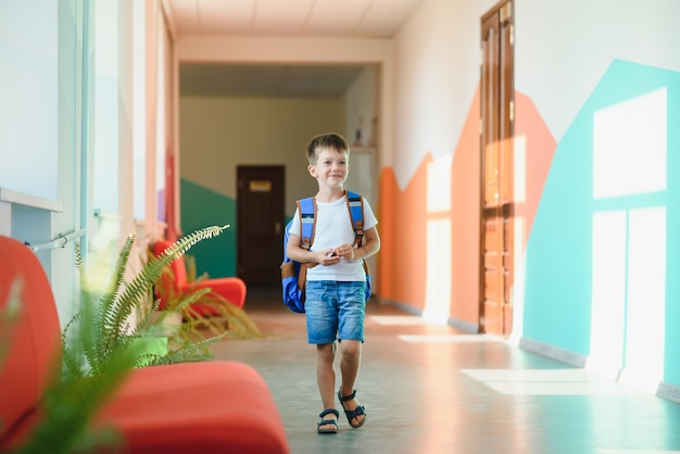 Schattige kleine schooljongen die op de gang van de school loopt