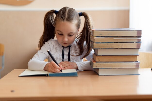 Schattige kleine schoolmeisje in haar uniform in de klas