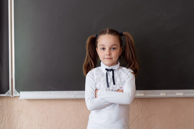 Schattige kleine schoolmeisje in haar uniform in de klas