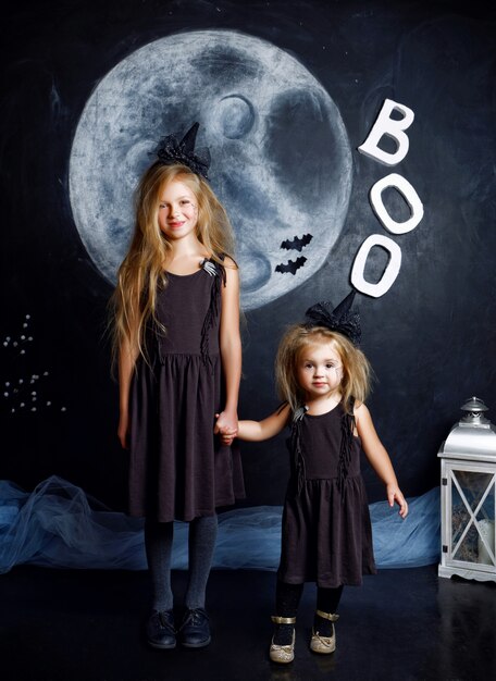 schattige kleine zusjes zijn gekleed in heksenkostuums