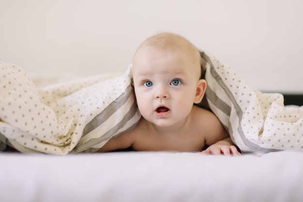 Schattige lachende baby spelen glimlachend poseren op het bed